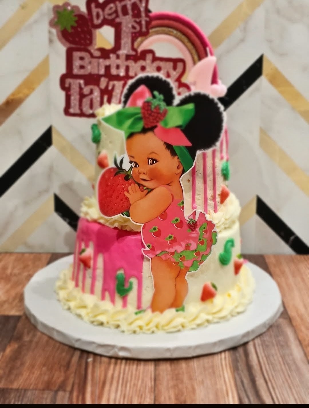 Berry first birthday cake with strawberry baby girl topper and pink drip