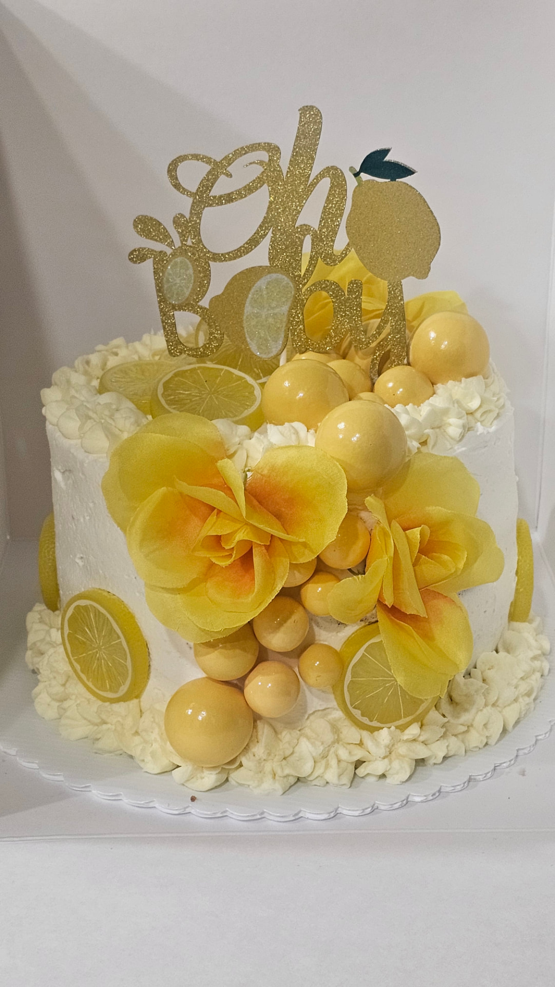 White lemon themed baby shower cake with yellow roses, lemon slices and an Oh Baby gold topper