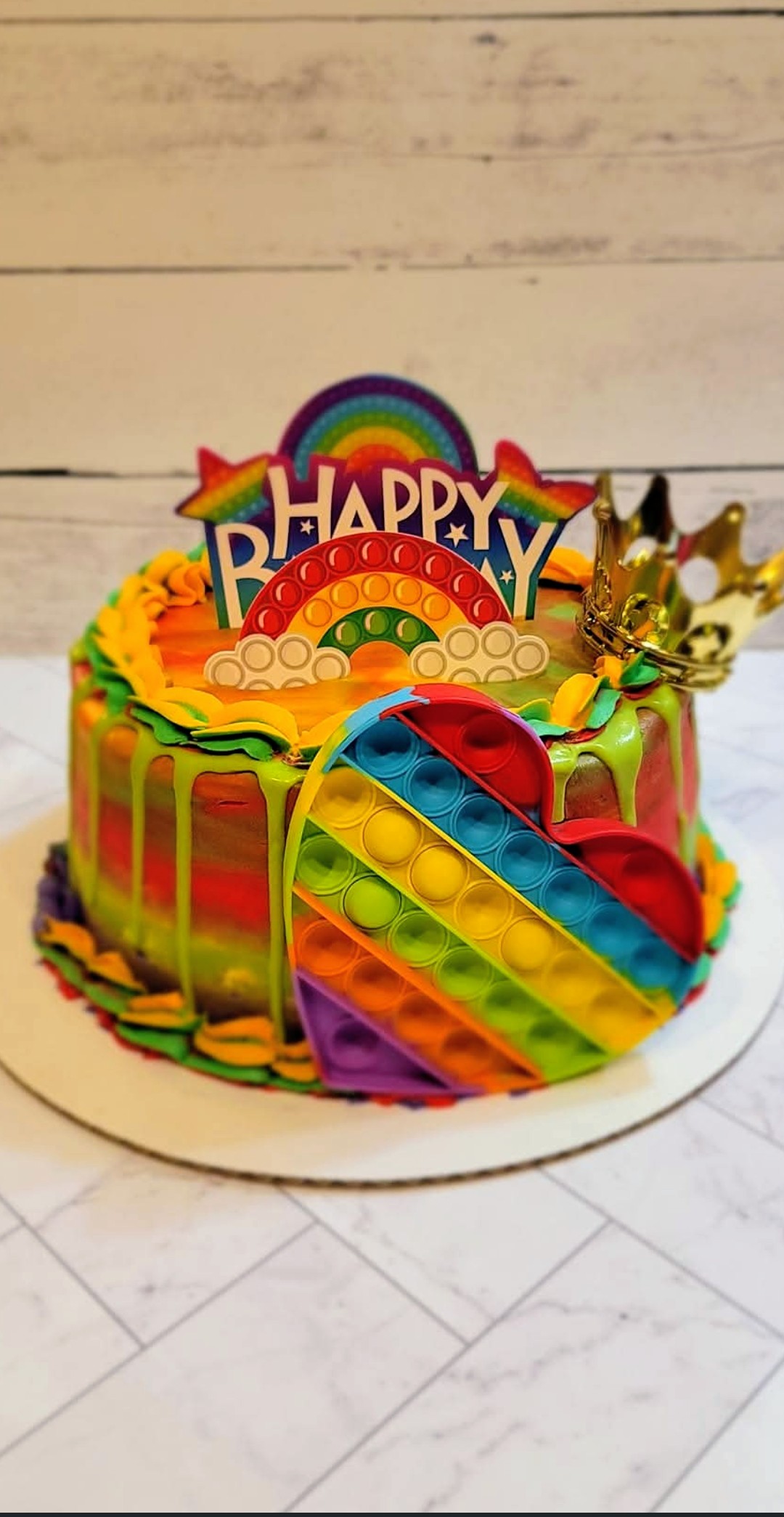 Rainbow pop-it themed birthday cake with colorful drip and Happy Birthday topper