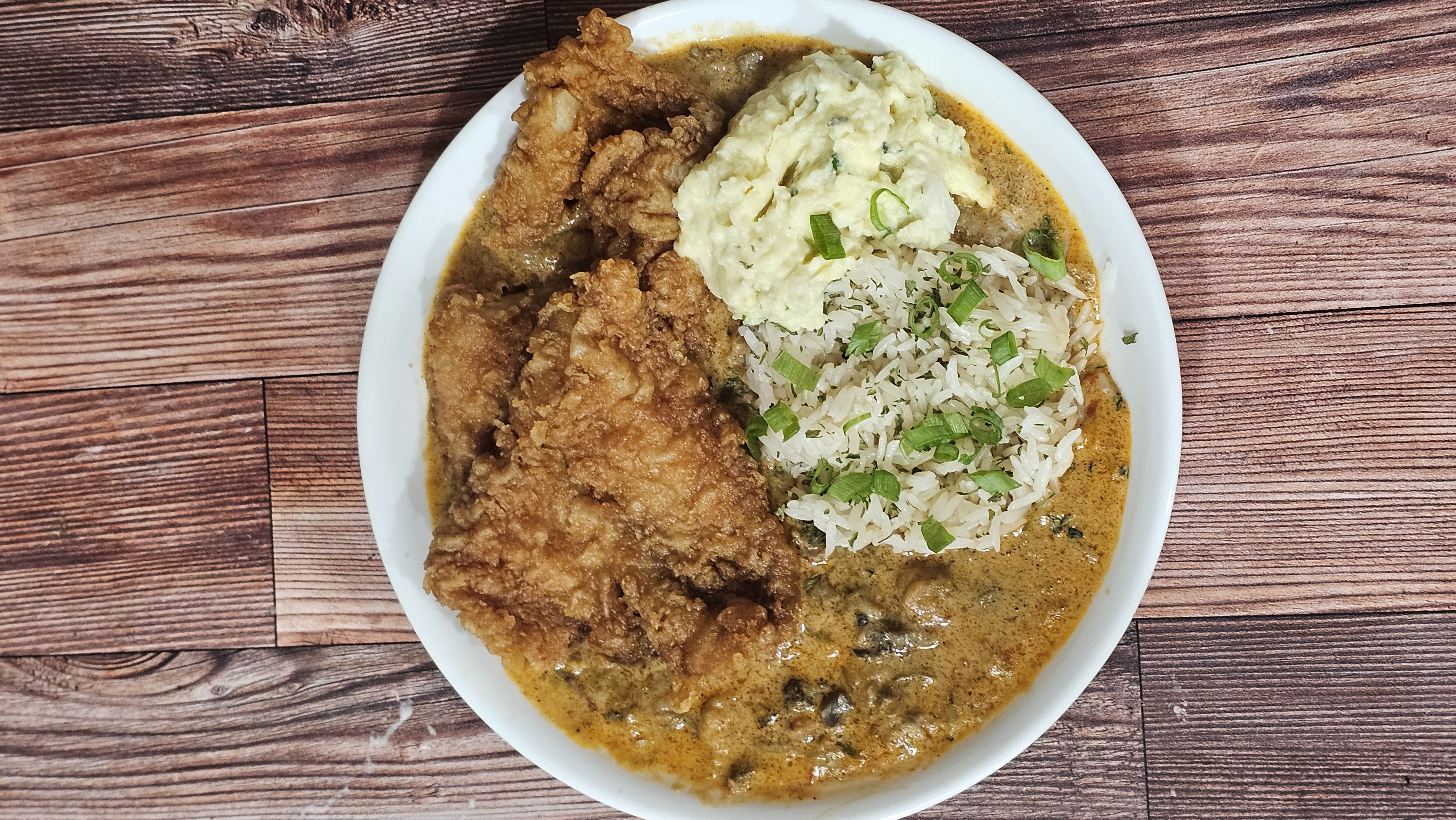 Golden fried chicken over creamy mushroom gravy with herbed rice and potato salad