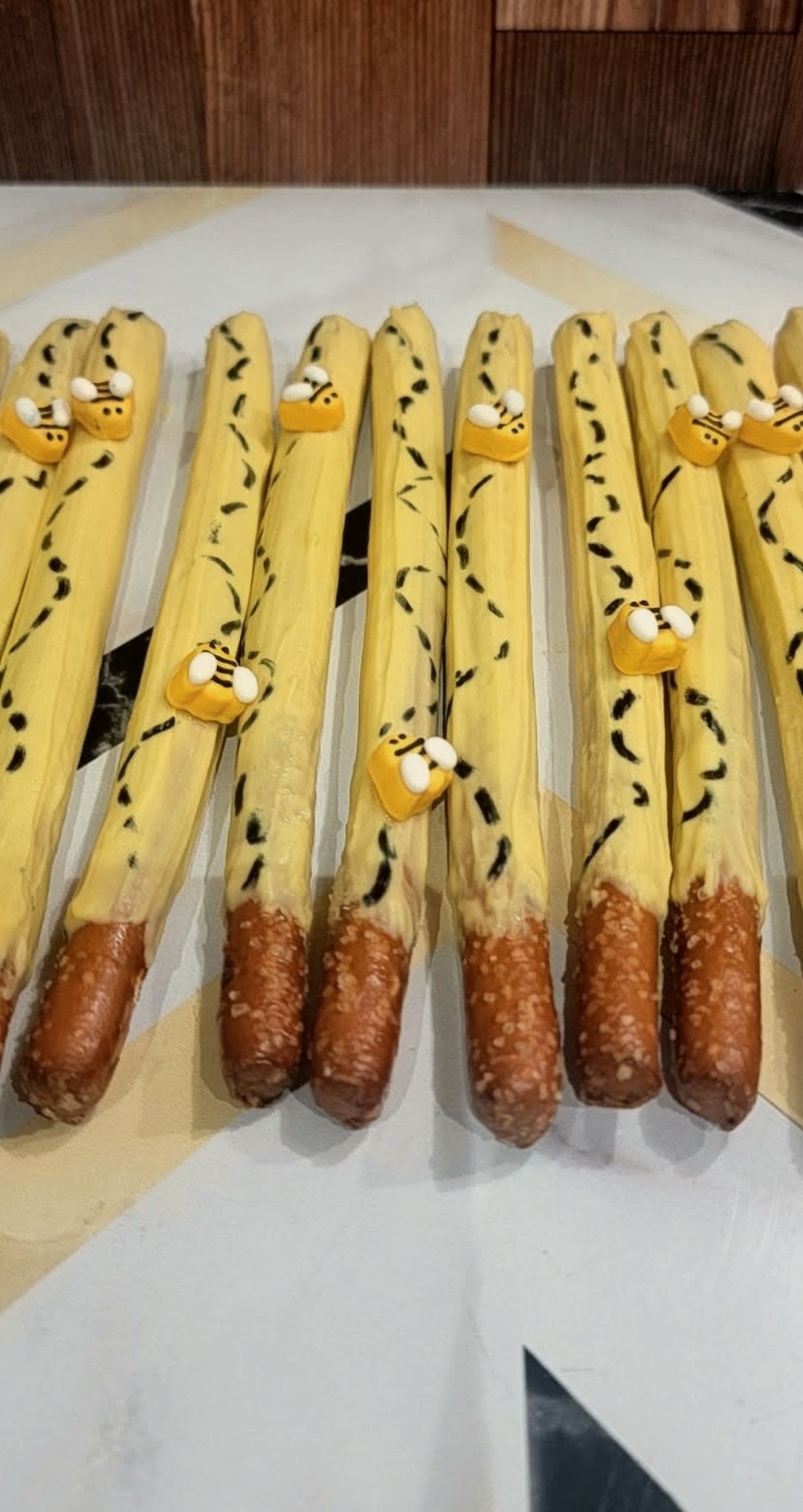 Bee themed chocolate covered pretzel rods with edible bees