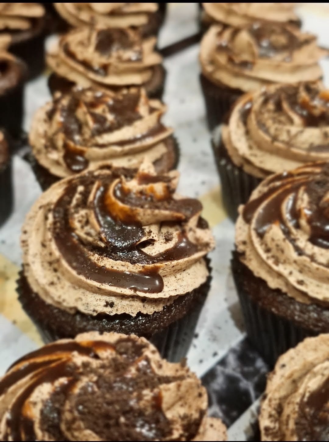 Chocolate cupcakes swirled with caramel frosting and chocolate drizzle