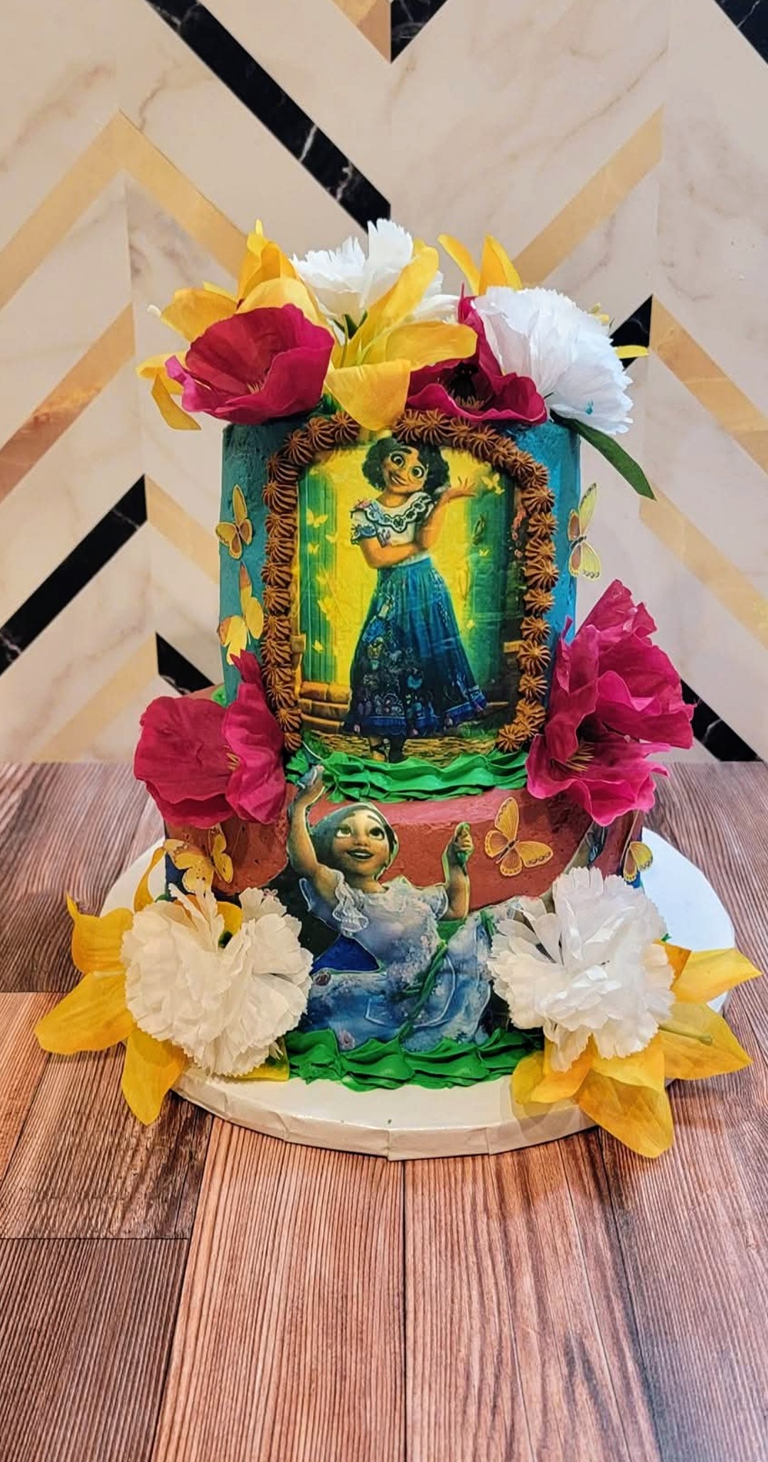 Encanto Mirabel themed two-tier birthday cake with bright flowers