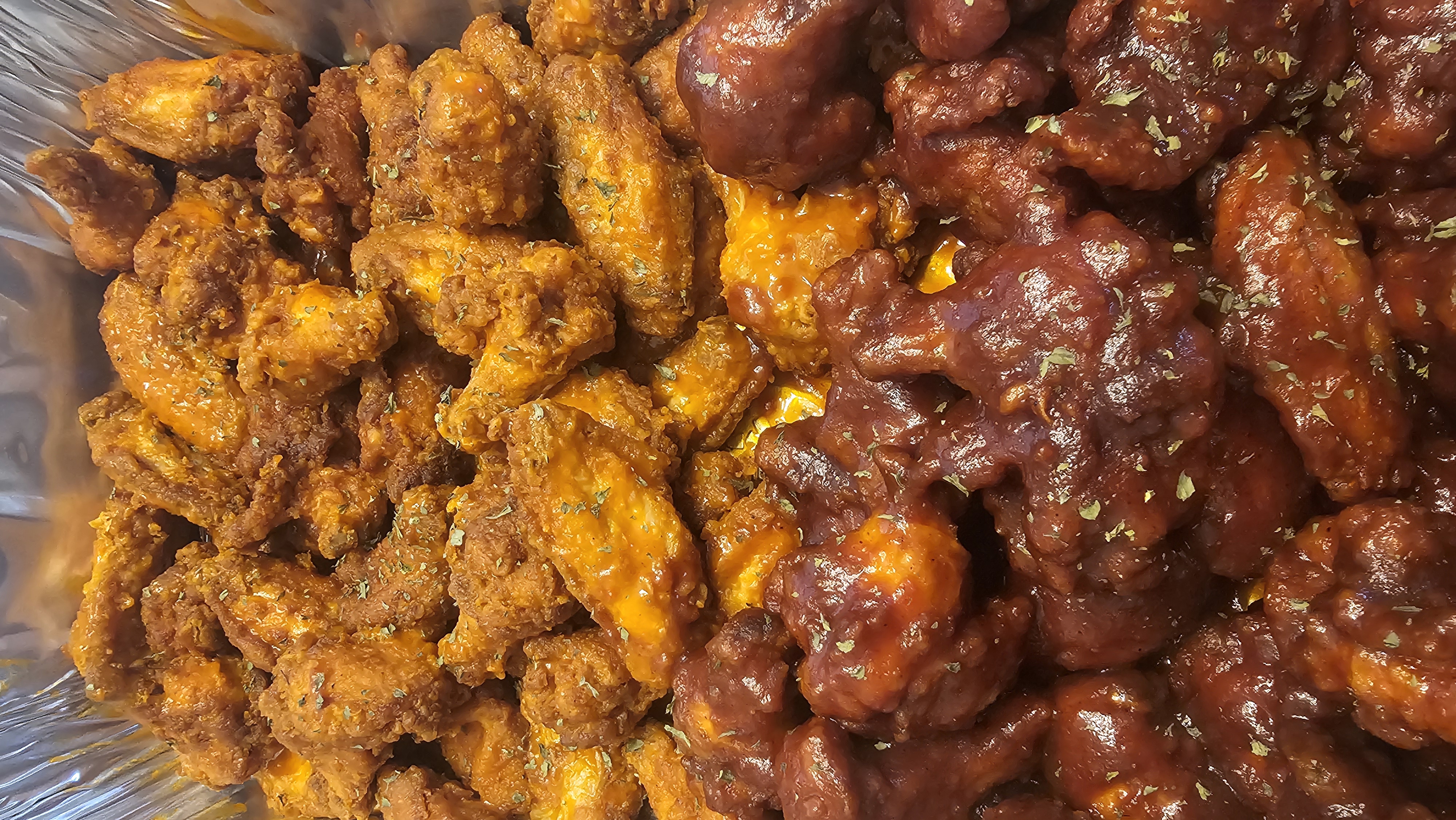 Catering tray of buffalo and barbecue wings dusted with herbs